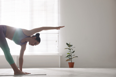 Photo of Young woman practicing extended triangle asana in yoga studio. Utthita Trikonasana pose