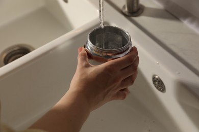 Woman washing moka pot at sink in kitchen, closeup