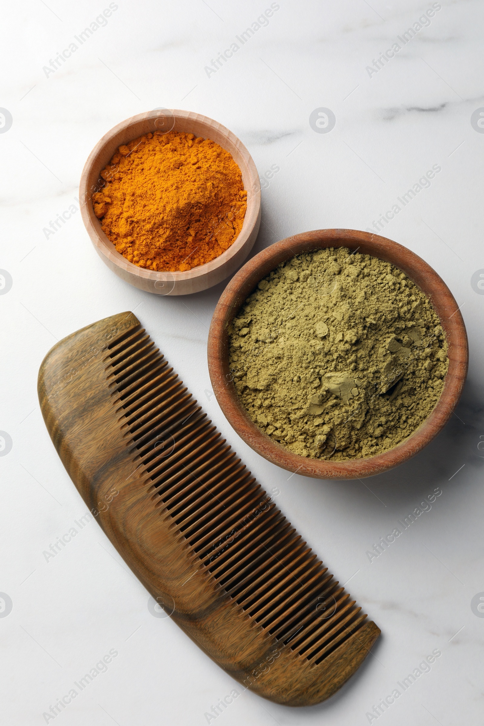 Photo of Comb, henna and turmeric powder on white marble table, flat lay