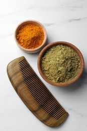 Photo of Comb, henna and turmeric powder on white marble table, flat lay