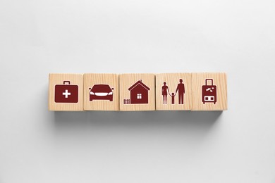 Image of Wooden cubes with different icons on white background, flat lay. Insurance concept