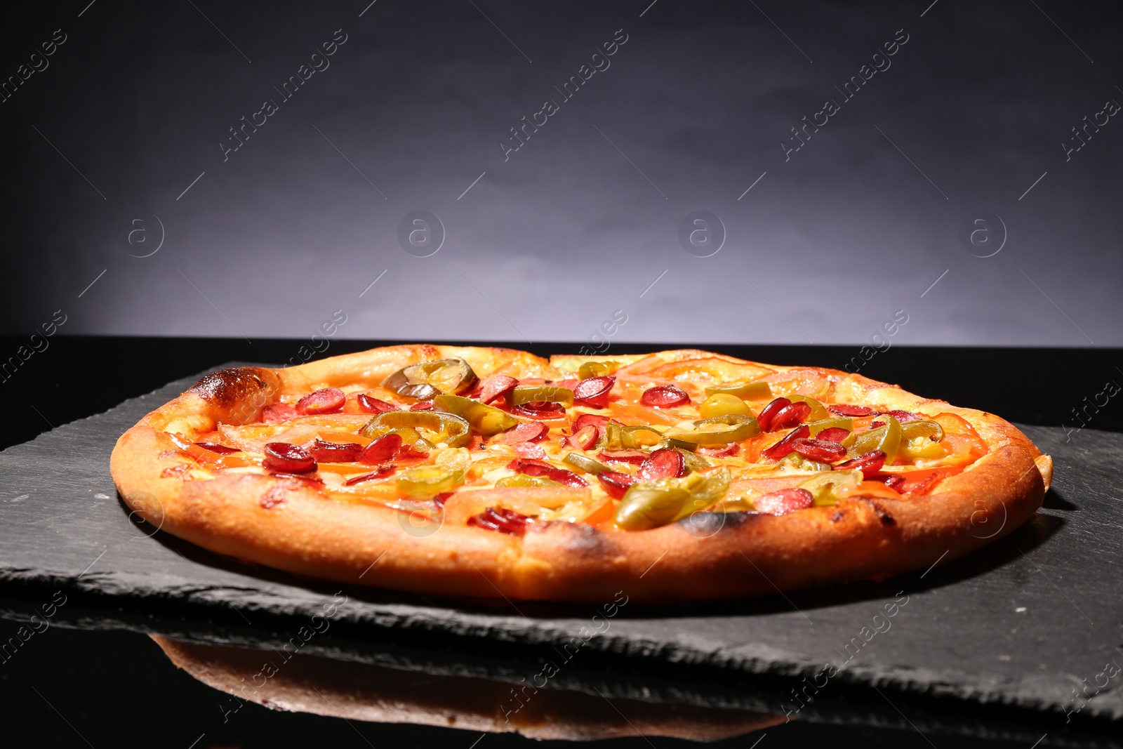 Photo of Delicious pizza Diablo on slate board against grey background