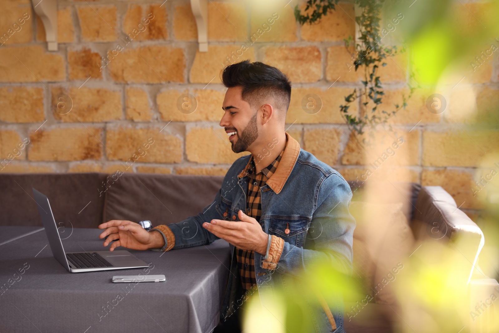 Photo of Young blogger working with laptop at table in cafe