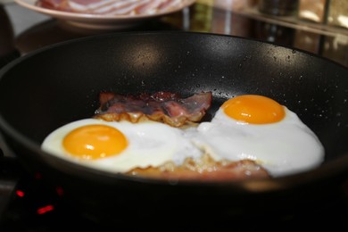 Cooking eggs with bacon in frying pan, closeup. Tasty breakfast