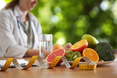 Image of Healthy products, measuring tape and blurred view of nutritionist outdoors