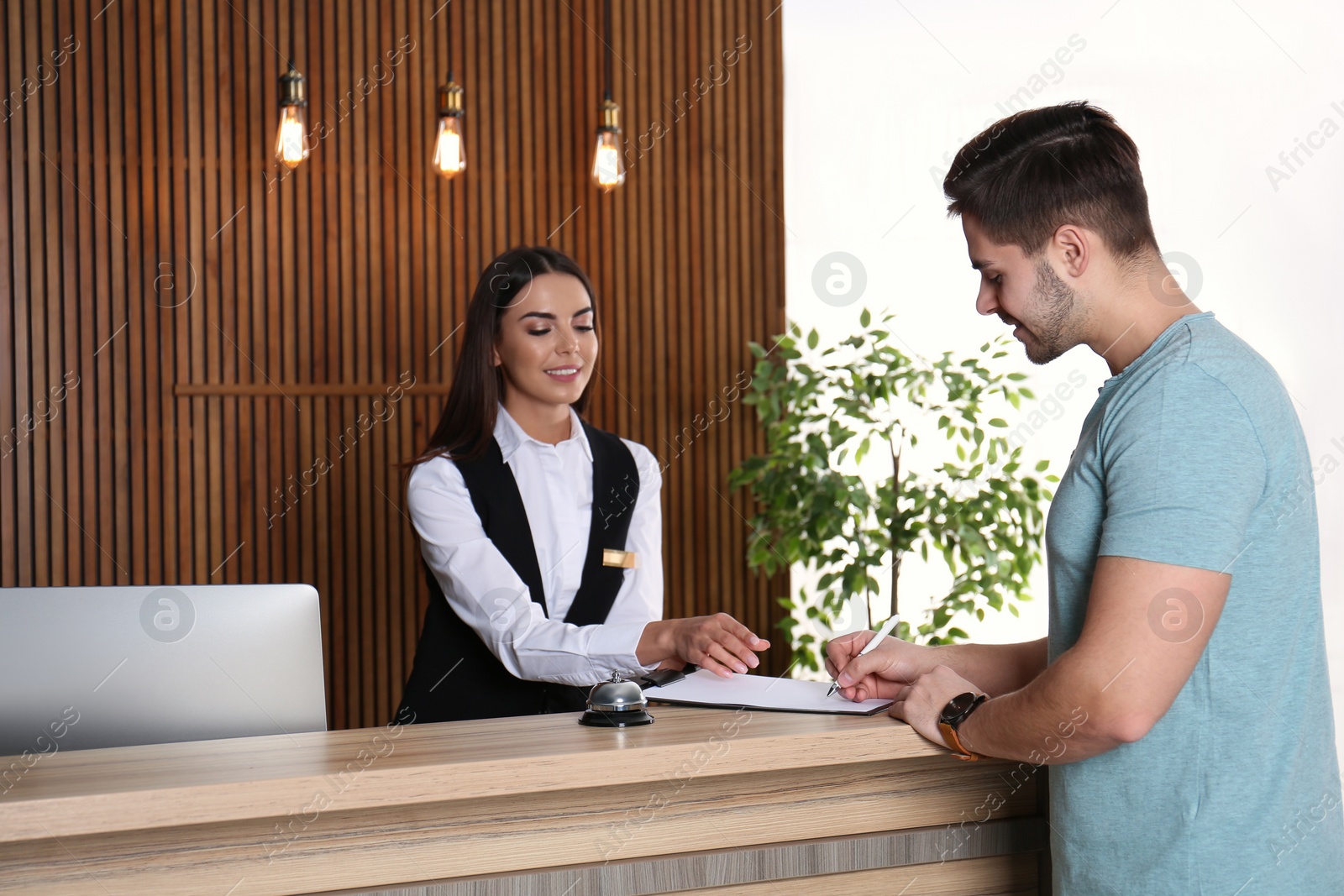 Photo of Receptionist registering client at desk in lobby