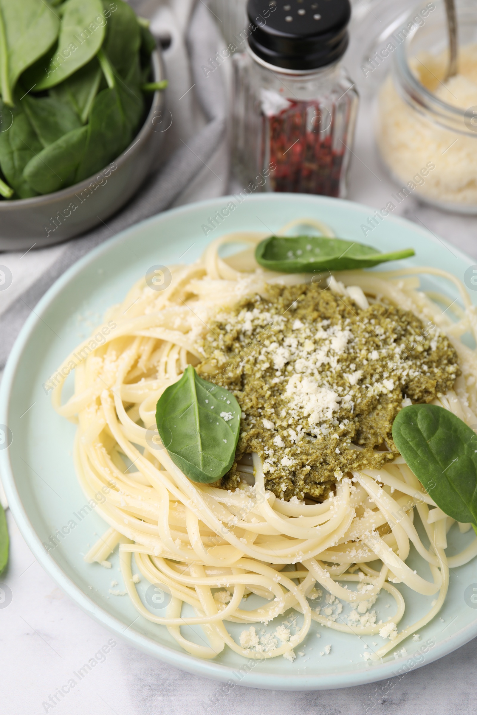 Photo of Tasty pasta with spinach, cheese and sauce on white marble table