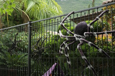 Photo of Big spider figures on black metal fence. Halloween decoration