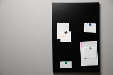 Photo of Many notes attached to magnetic black board on grey wall, space for text