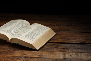 Photo of Bible on wooden table, space for text. Religion of Christianity