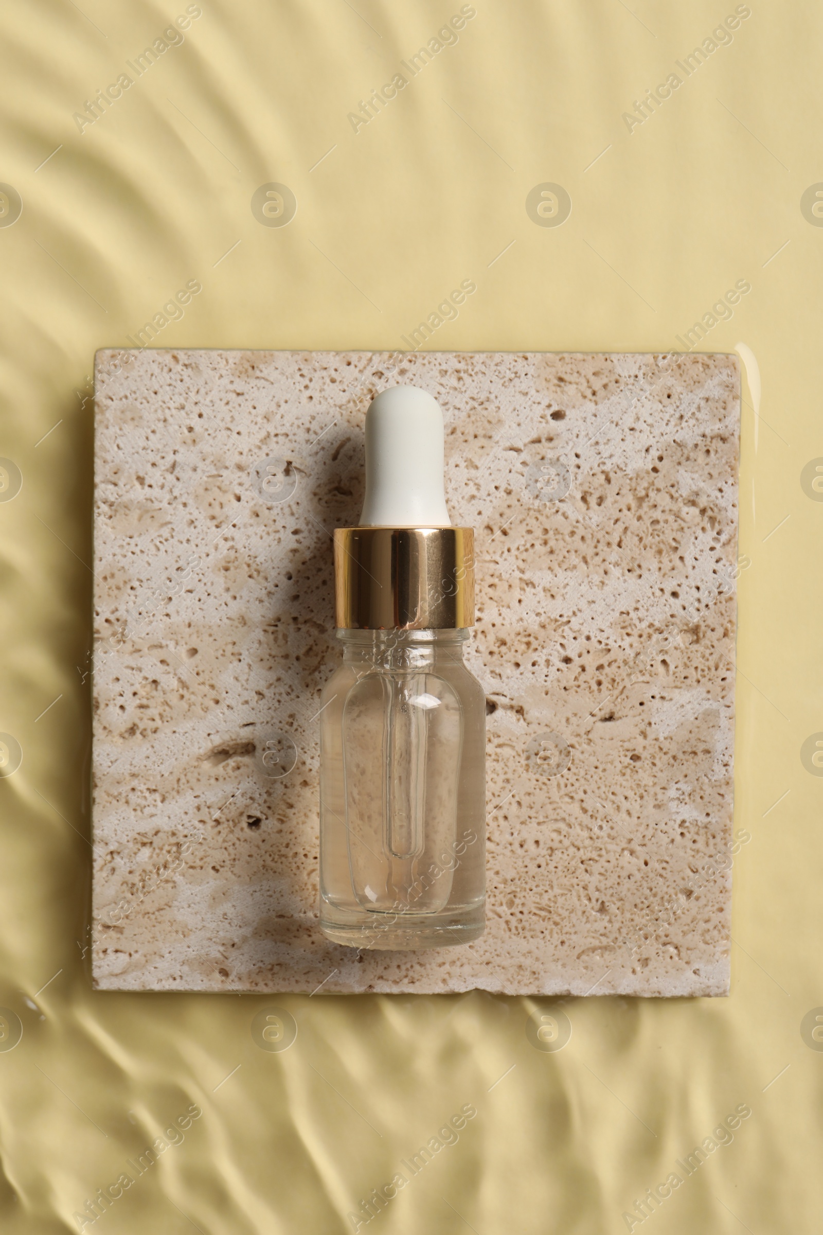 Photo of Bottle of cosmetic serum and water on beige background, top view