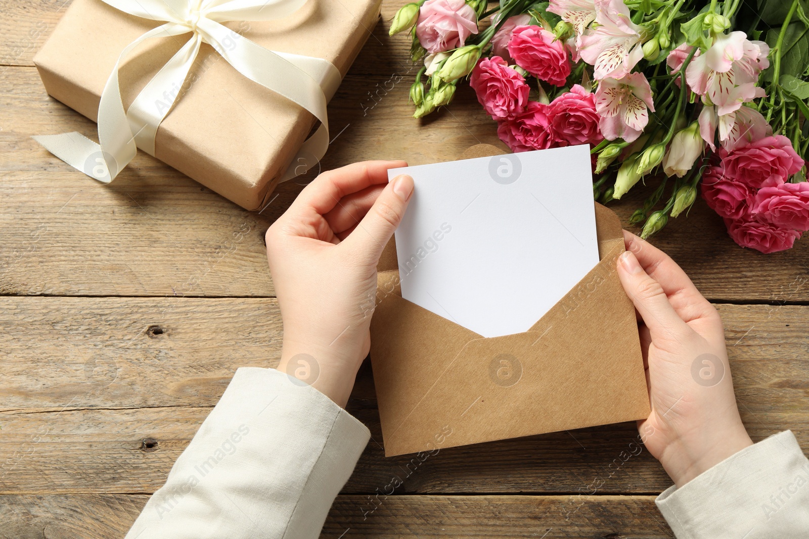 Photo of Happy Mother's Day. Woman holding envelope with blank card at wooden table, top view