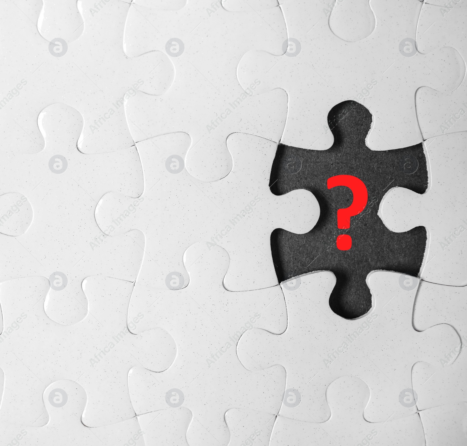 Image of White puzzle with missing piece and question mark on black background, top view