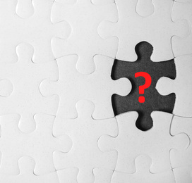 Image of White puzzle with missing piece and question mark on black background, top view