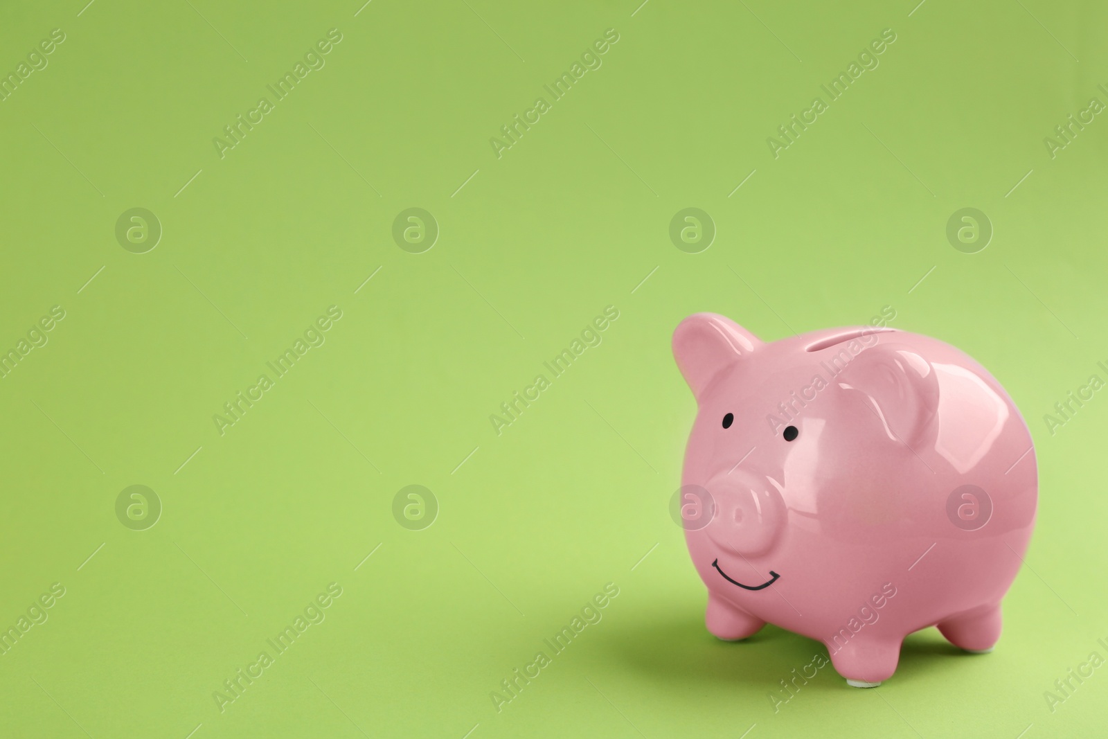 Photo of Pink piggy bank on green background. Space for text