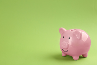 Photo of Pink piggy bank on green background. Space for text