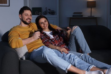 Photo of Happy couple watching TV at home in evening