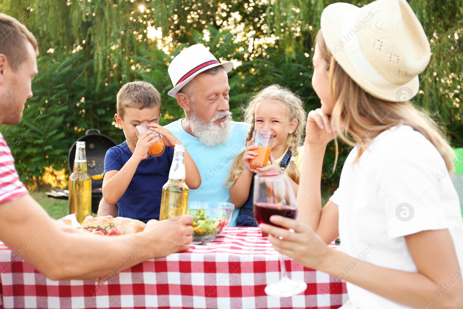 Photo of Happy family having barbecue in park on sunny day