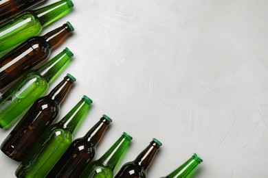 Glass bottles of beer on white background, flat lay. Space for text