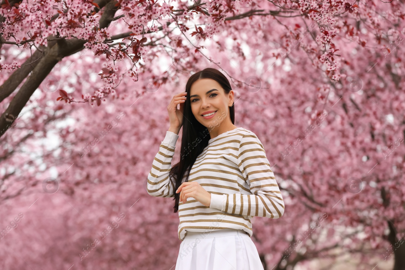 Photo of Pretty young woman in park with blooming trees. Spring look