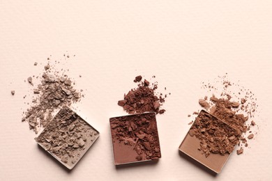 Different crushed eye shadows on beige background, flat lay. Space for text