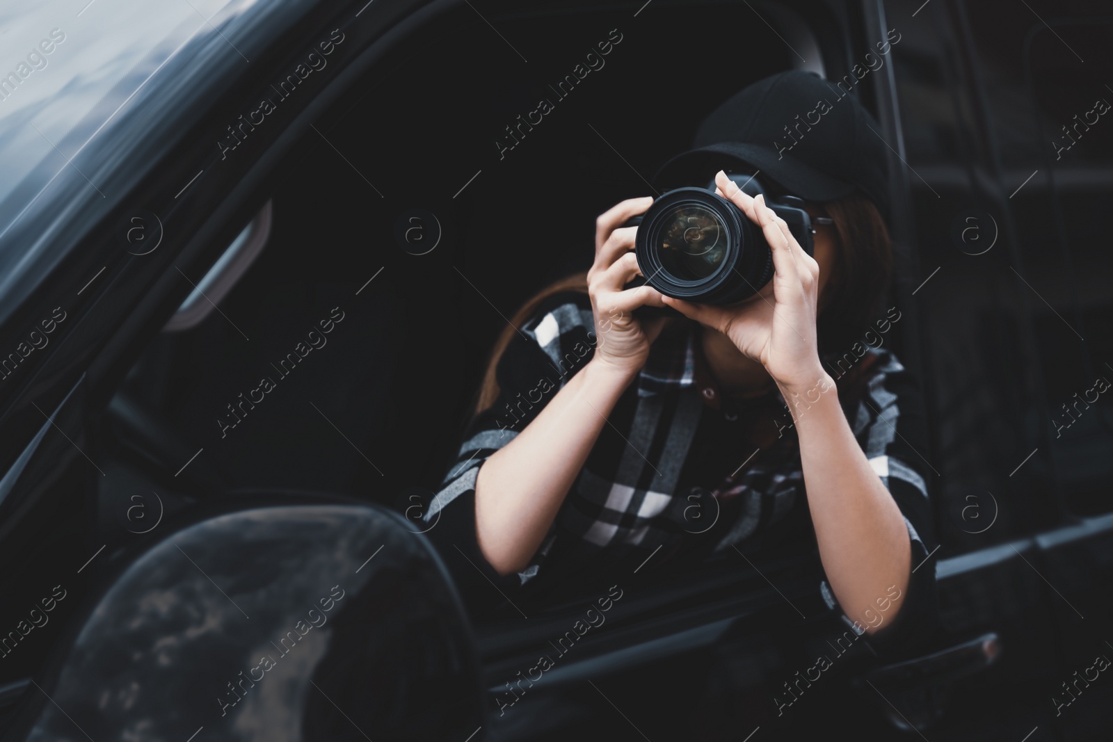 Photo of Private detective with camera spying from car