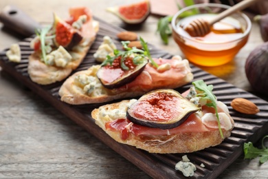 Photo of Sandwiches with ripe figs and prosciutto served on wooden table, closeup