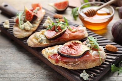 Sandwiches with ripe figs and prosciutto served on wooden table, closeup