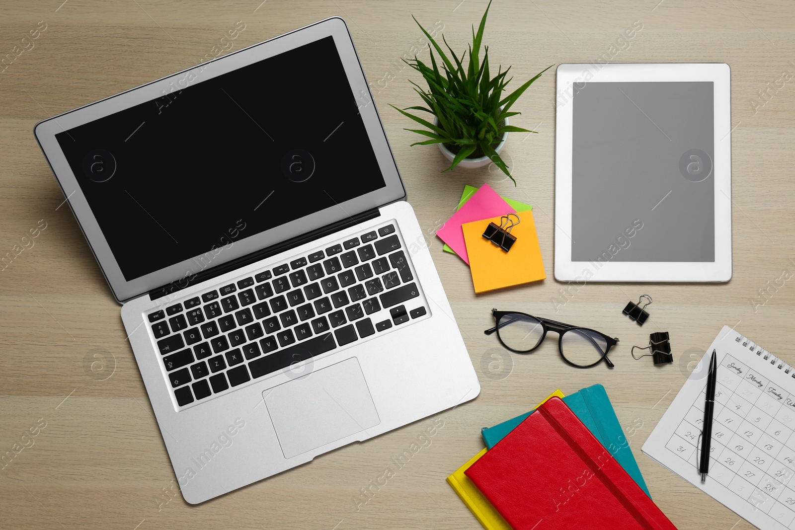Photo of Modern gadgets, glasses and office stationery on wooden table, flat lay. Distance learning