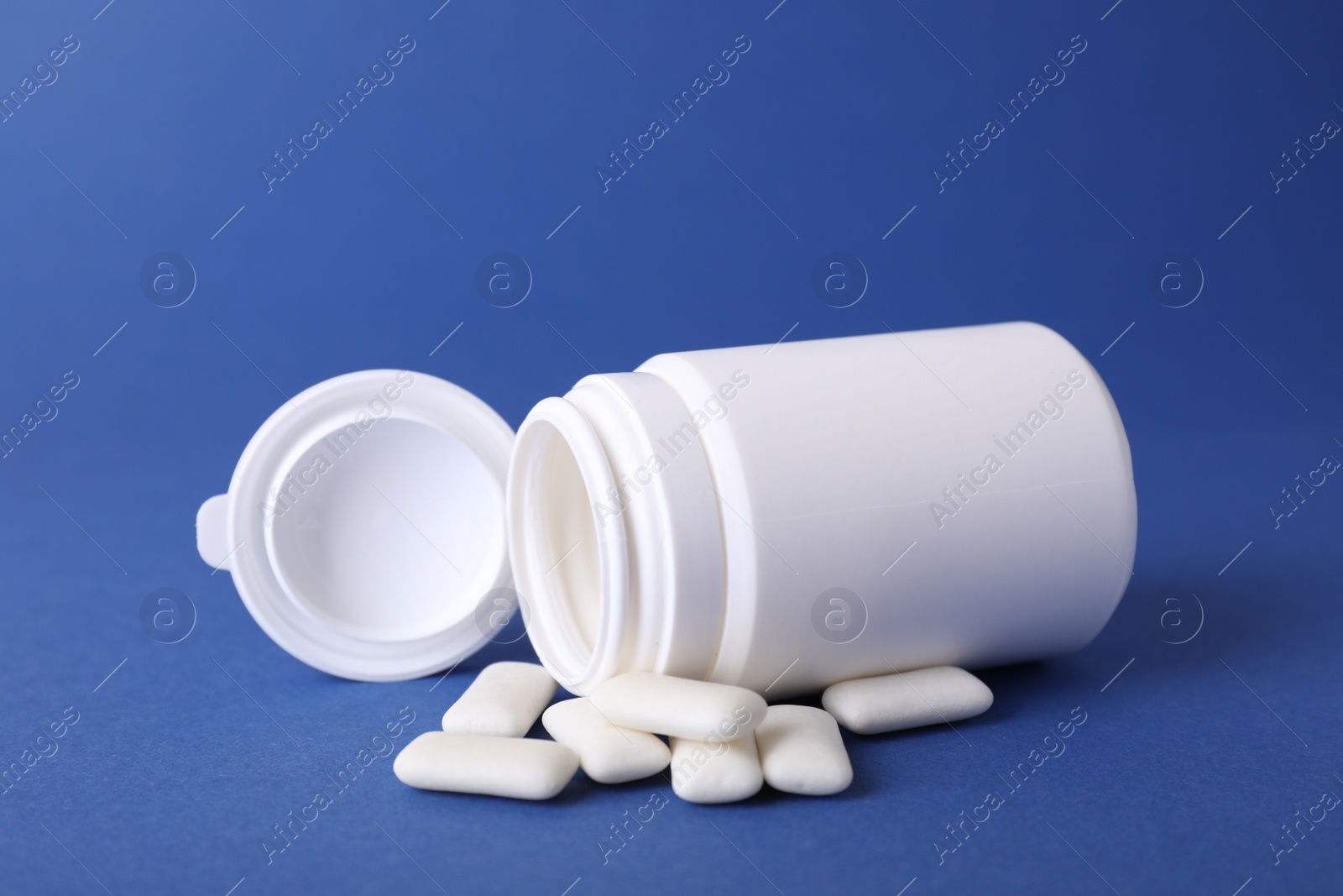 Photo of Jar with chewing gums on blue background