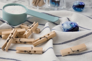 Photo of Wooden clothespins, detergent laundry pods and powder on fabric, closeup