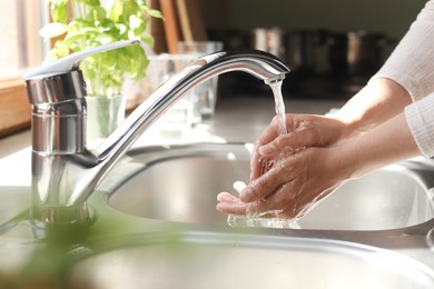 Photo of Woman washing hands in kitchen, closeup view