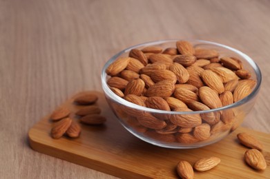 Bowl of delicious almonds on wooden table