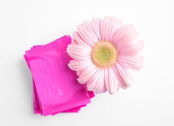 Stack of menstrual pads and gerbera flower on white background, top view. Gynecological care