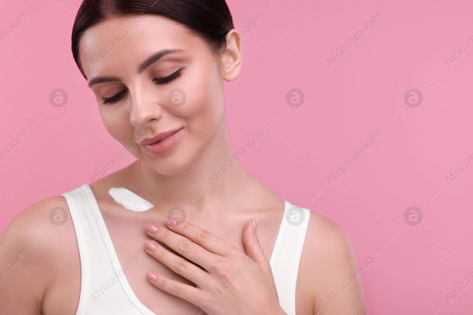 Photo of Beautiful woman with smear of body cream on pink background, space for text