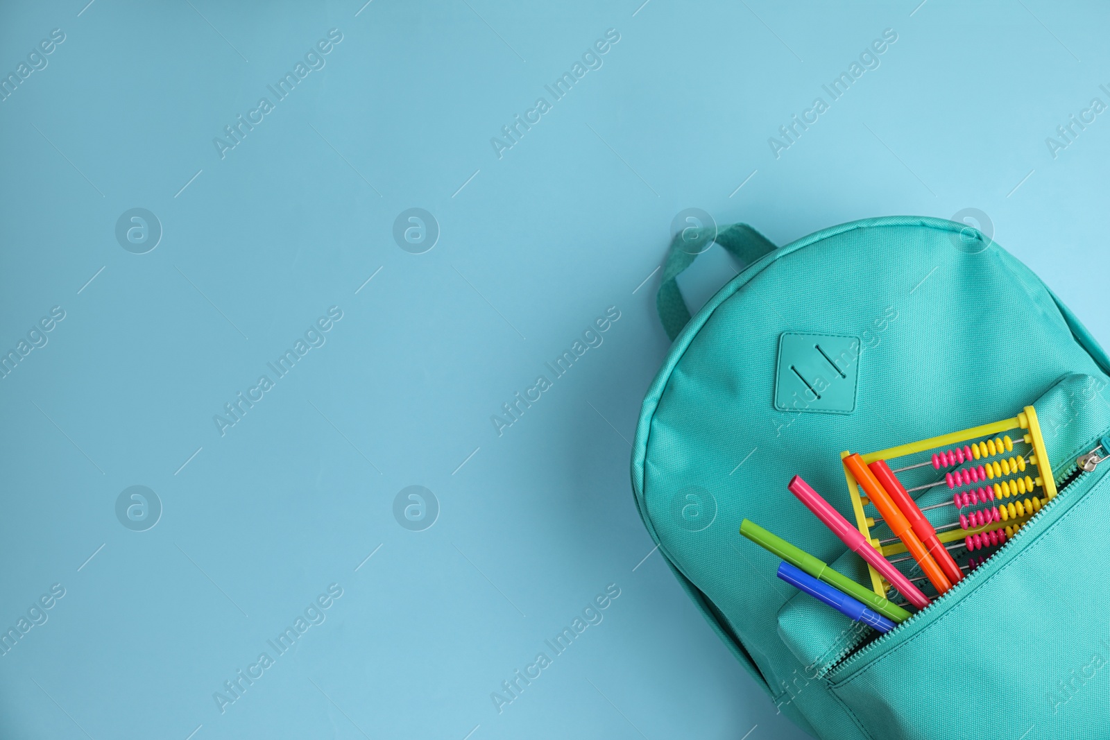 Photo of Stylish backpack with different school stationary on light blue background, top view. Space for text
