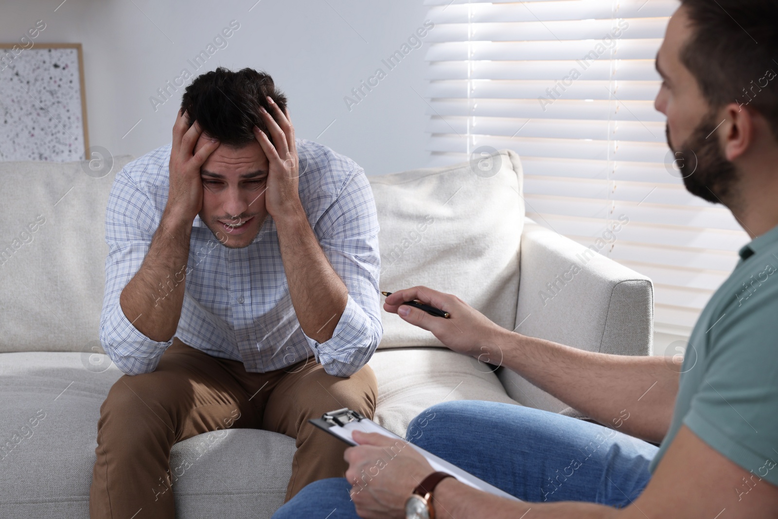 Photo of Unhappy man having session with his therapist indoors