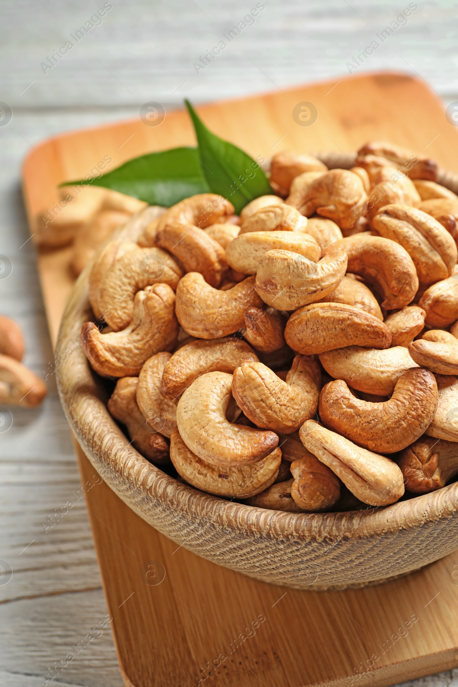 Photo of Bowl with cashew nuts on wooden table, closeup