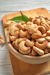 Photo of Bowl with cashew nuts on wooden table, closeup