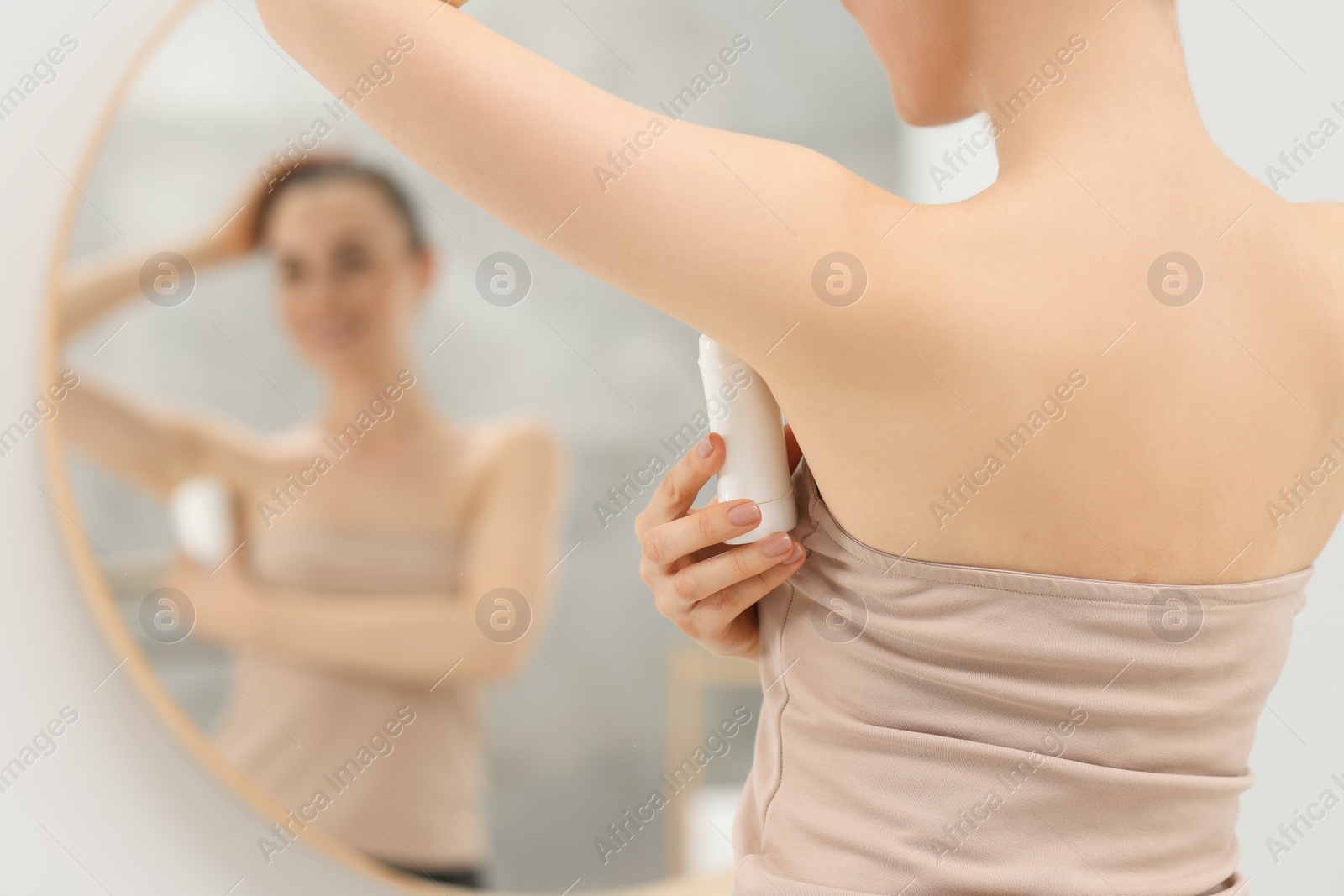 Photo of Beautiful woman applying deodorant near mirror in bathroom, selective focus