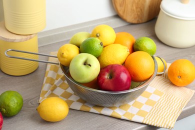 Metal colander with different fruits on countertop in kitchen