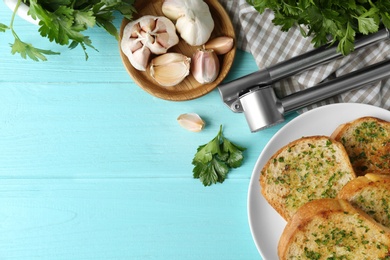 Photo of Slices of toasted bread with garlic and herbs on blue wooden table, flat lay. Space for text