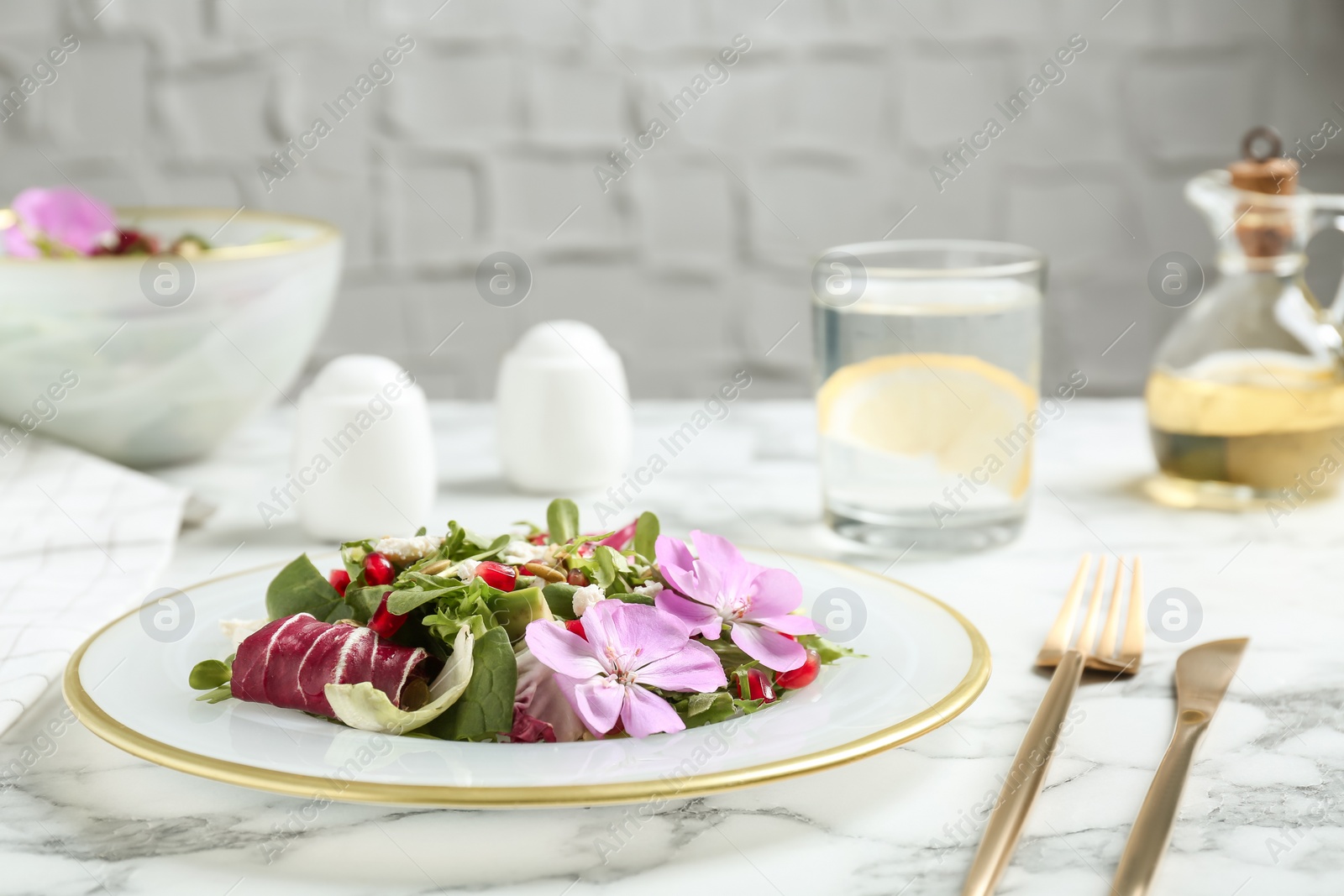 Photo of Fresh spring salad with flowers served on white marble table