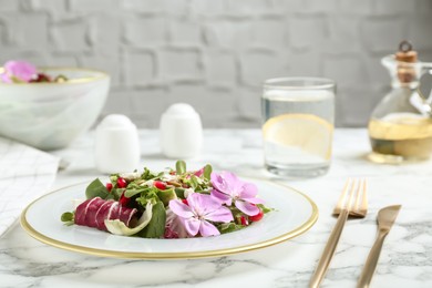 Fresh spring salad with flowers served on white marble table