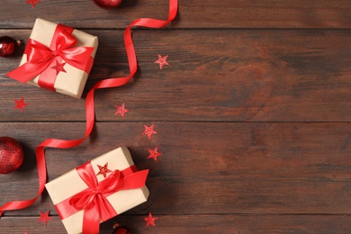 Photo of Flat lay composition with Christmas gift boxes and decor on wooden table, space for text