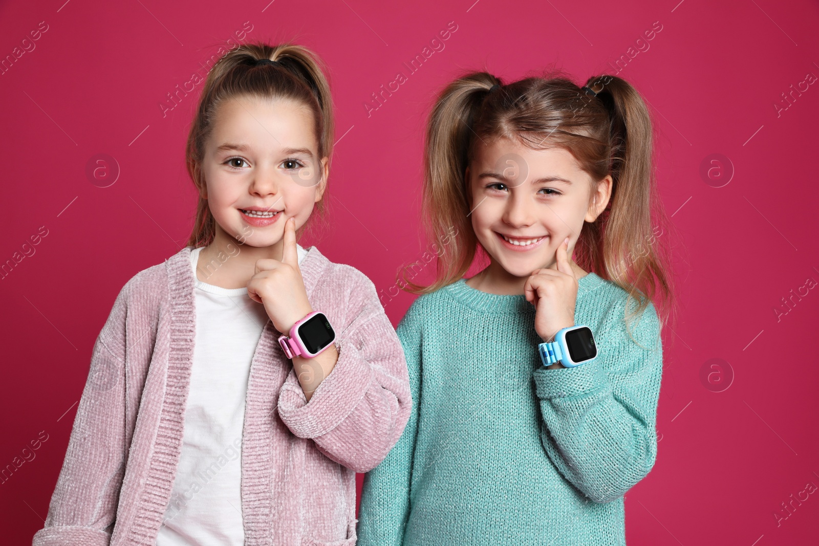 Photo of Little girls with smart watches on pink background