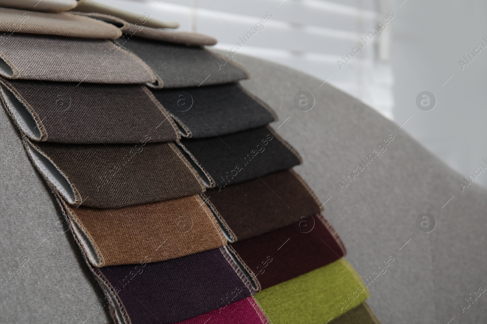 Photo of Catalog of colorful fabric samples on grey sofa indoors, closeup. Space for text