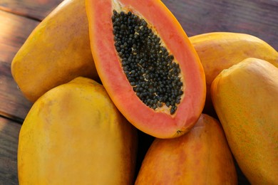 Photo of Fresh ripe cut and whole papaya fruits on wooden table, closeup