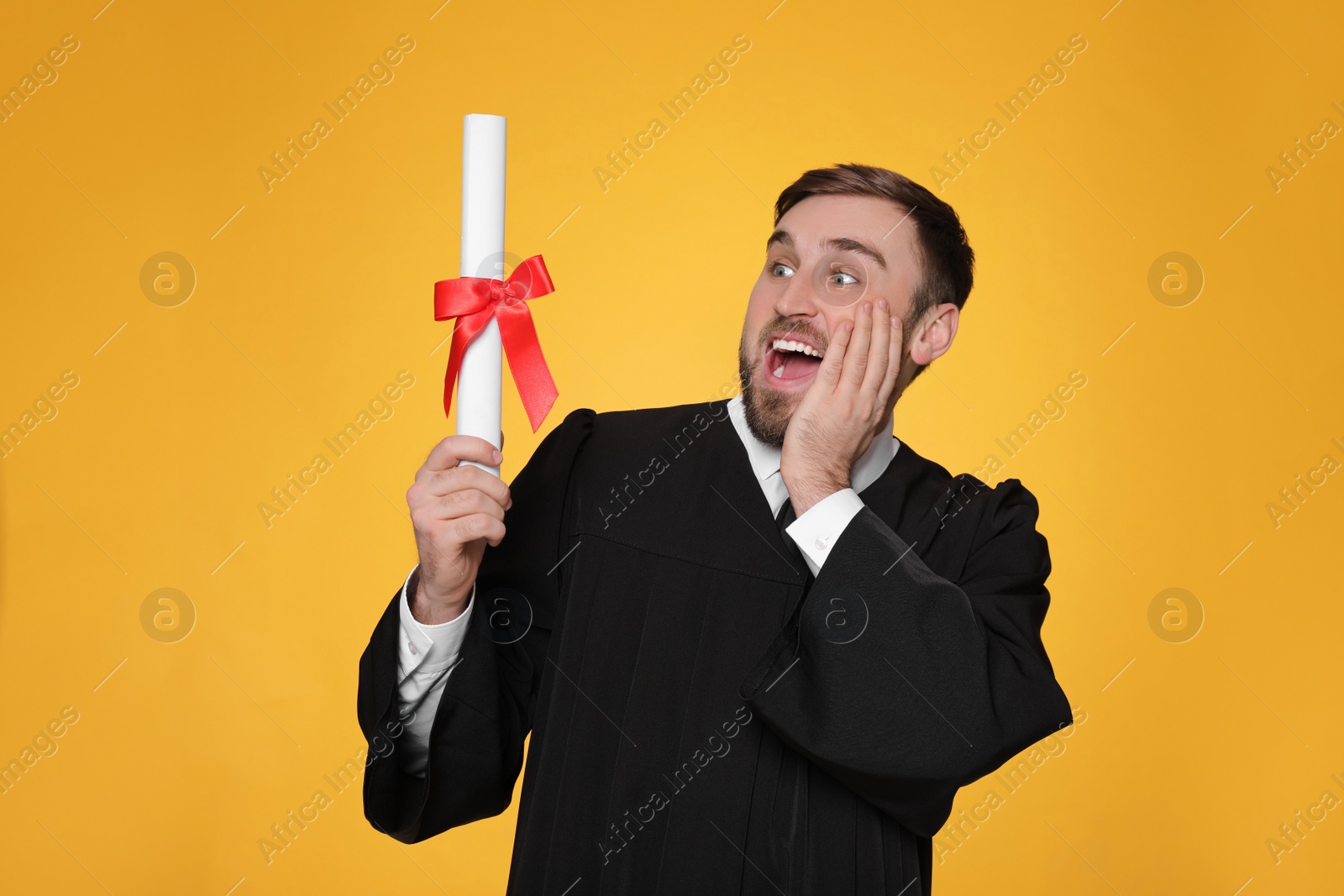 Photo of Emotional student with diploma on yellow background