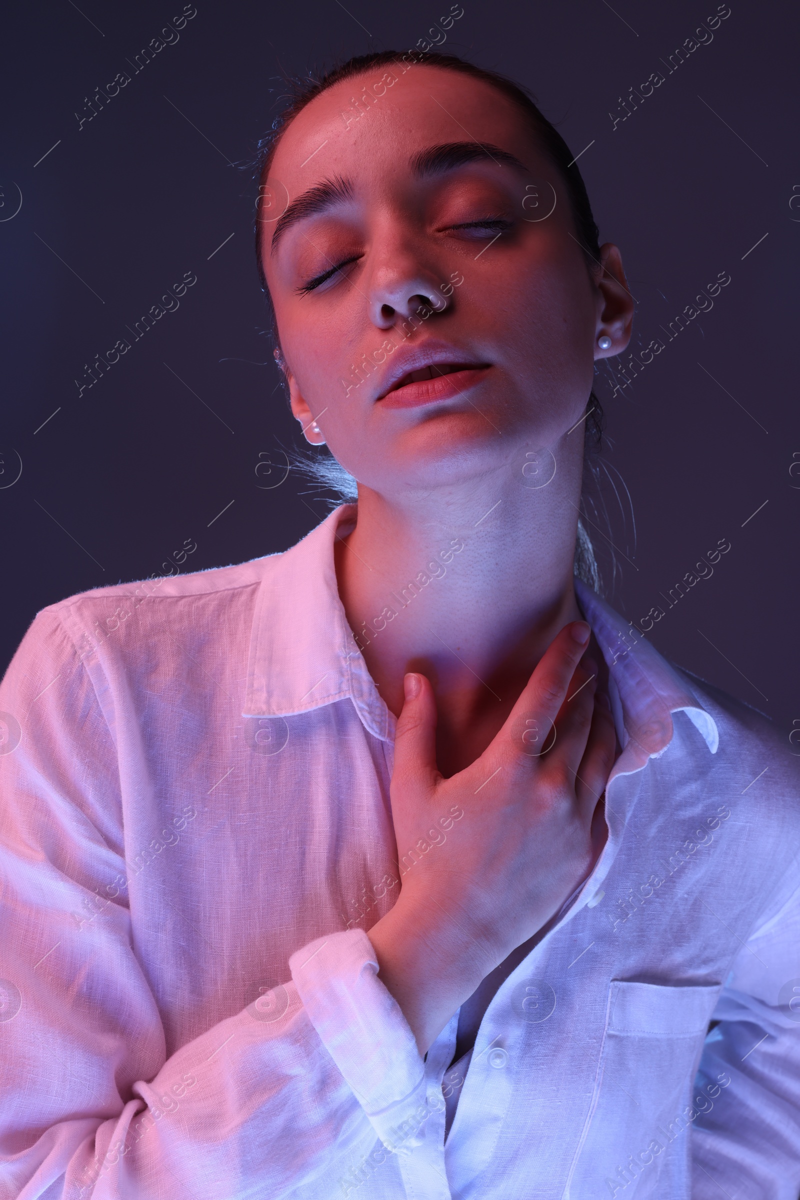 Photo of Portrait of beautiful young woman on dark purple background with neon lights